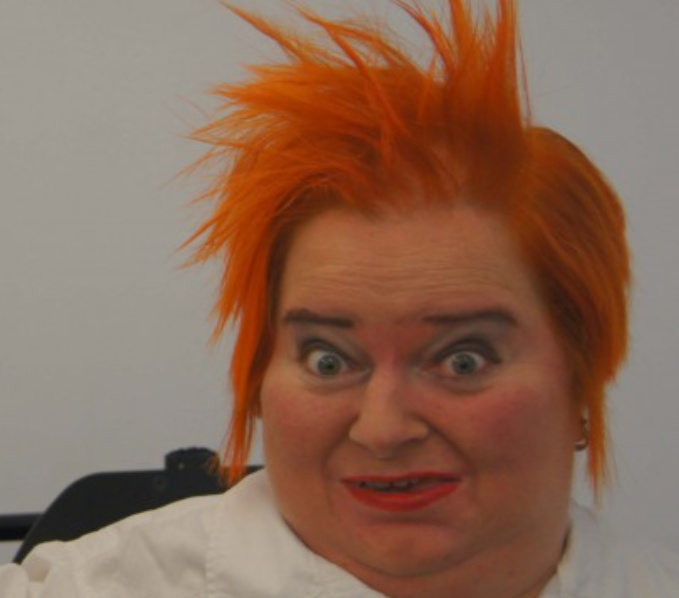 The Disabled Artist and legend Katahrine Araniello. In this headshot she has bright orange hair.
