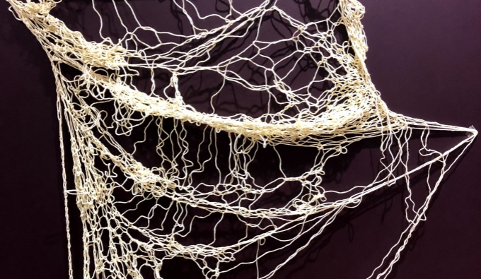 A black background with a tangled, net-like woven string.