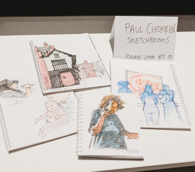 A series of pencil sketches on white paper laid out on a table.