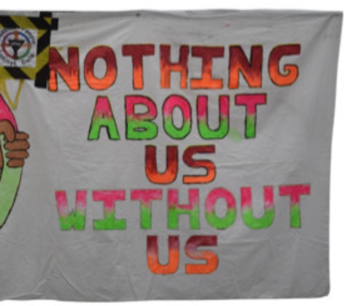 A white fabric banner with text which reads nothing about us without us in colourful capital letters.