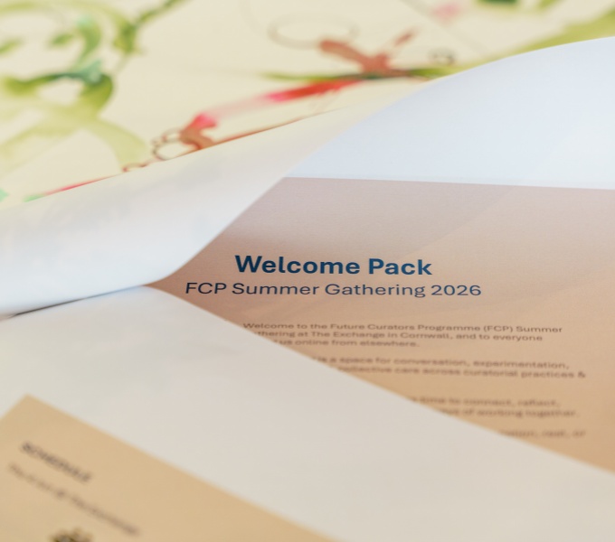 A close up of the folded pages of the Summer Gathering Welcome pack. The text on the page is dark blue and the page colour a peachy orange.