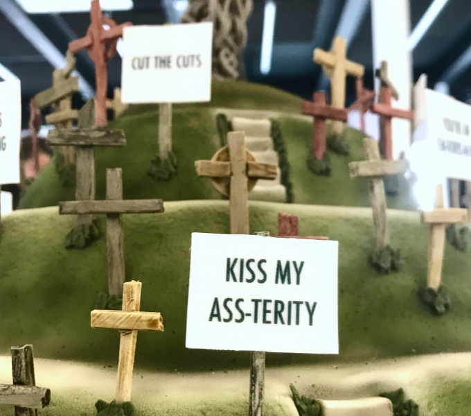 A sign on a hill shaped cake reads 'Kiss My Ass-terity'