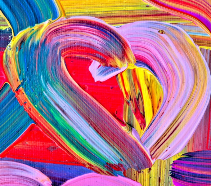 An abstract heart is painted onto a background of reds, pinks, yellows and blues. The canvas is thick with paint and the heart shape is created through the brush stroke rather than separate colours.