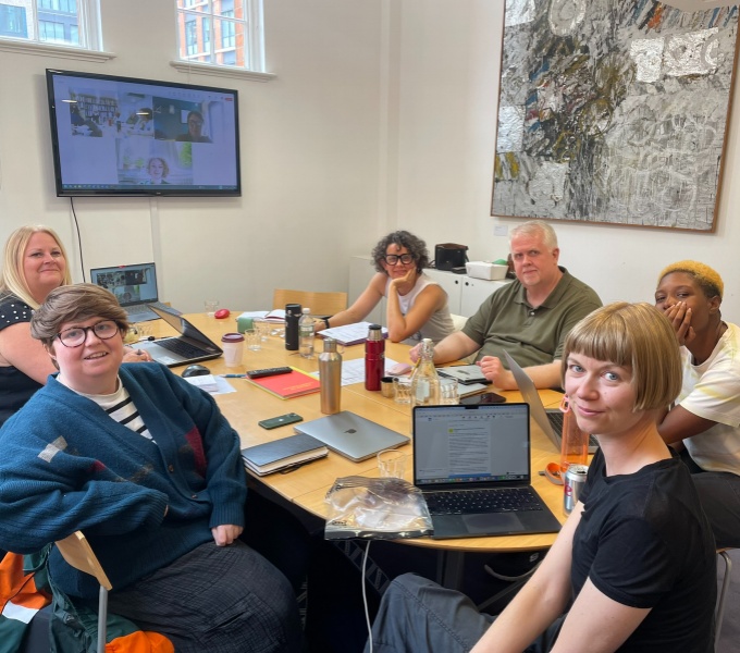 6 members of the dash team sit around an oval table, joined by two members attending remotely via a wall-mounted monitor.
