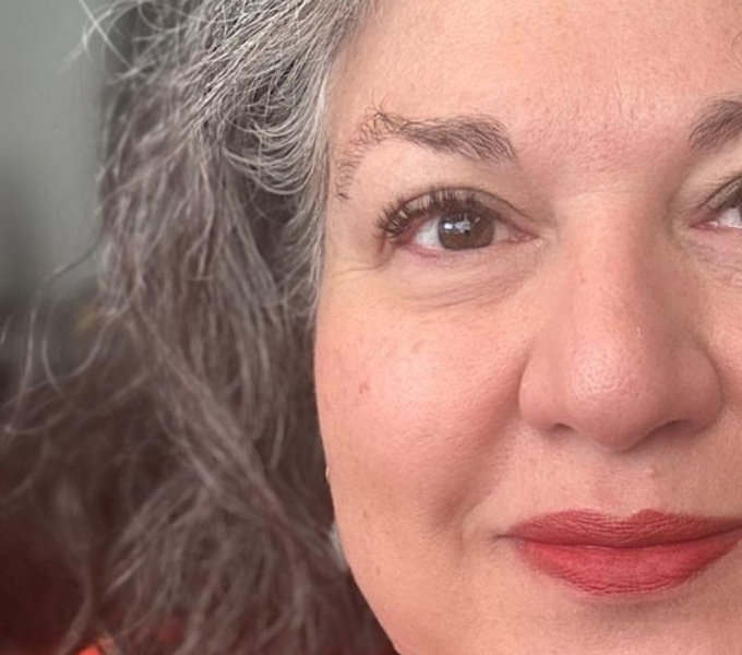 Image is a close up of Eleonora Belfiore, a white woman with brown eyes, grey brown heair and wearing red lipstick.