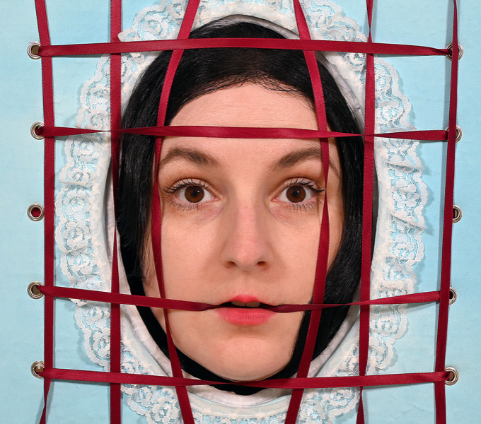 A face protrudes through a hole in a blue background with a red tape grid over the top.