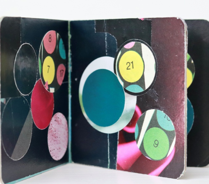 small collage board book with mainly black and brown backgrounds featuring colourful circles. The front cover features two hands.