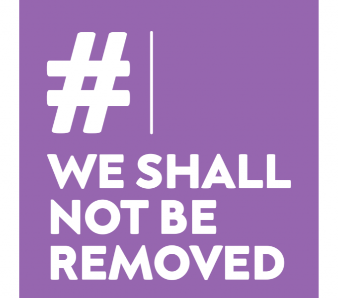 Purple, square logo with #We Shall Not Be Removed in white font