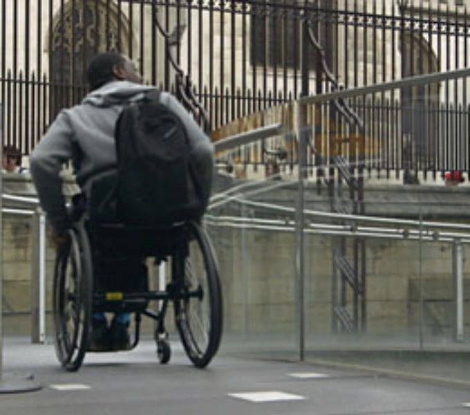 A wheelchair user navigates a ramp in an urban setting