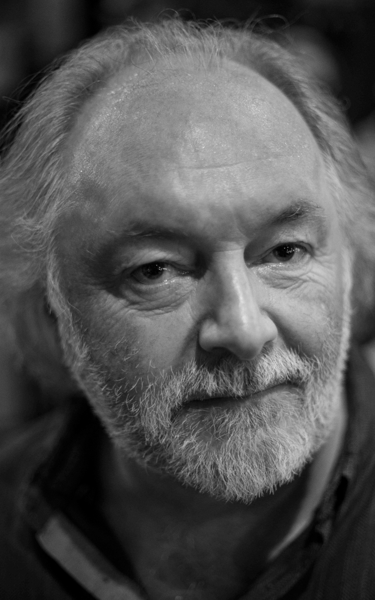 A black and white portrait photo of Chris.  He has a mid length white beard and dark shirt.