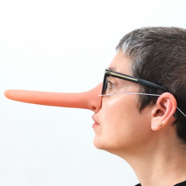 A side profile photographic portrait of Sonia with oversized elongated nose. She wears pink glasses and a black knitted hat.