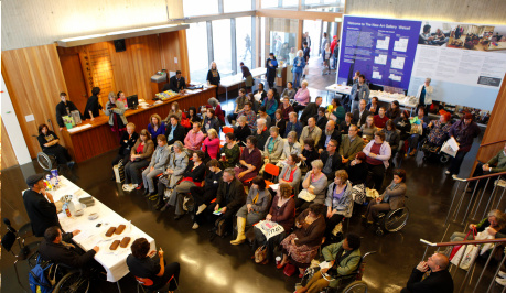 Photo of many people, taken from above,  gathered for the launch event inside a wooden panelled building