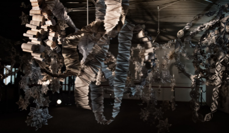 Paper streamers hand down in loops from the ceiling. Some are rolls of printed paper or concertinaed fans, while others take the form of snowflakes. 