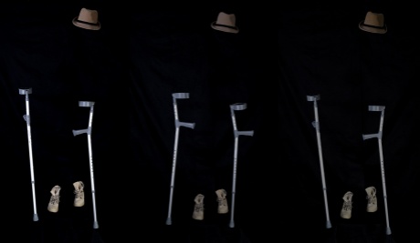 A dark background with three floating hats, 3 pairs of crutches and brown boots. It is as if there is an invisible person wearing them. As the image moves from left to right the crutches, hats and shoes become more faded.