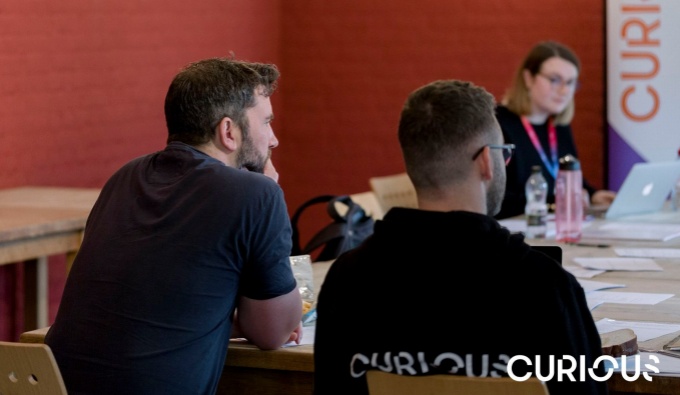 Image shows participants in a room with deep orange walls undertaking a training course.