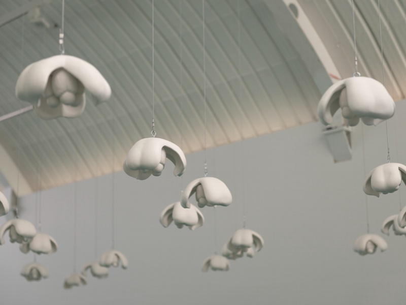 White sculptures of ackee fruit hang from the white ceiling