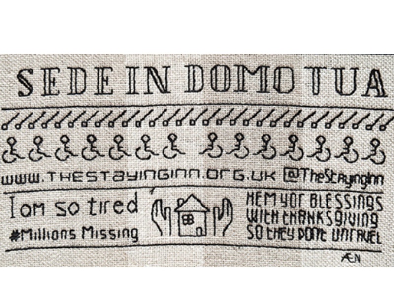Sampler from the Staying Inn panel. White fabric with embroidered slogan; Sede in Domo Tua and wheelchair symbols below. Also embroidered are the phrases; I am so tired, #Millions Missing and Hem Yor Blessings with thanksgiving so they don't unravel.