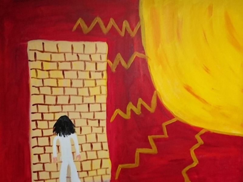 A pillar box red painted background. To the right a large bright yellow sun, jagged rays like lightening stretch across the canvas. To the left a block brick wall. A figure wearing white, with long black hair stands facing the wall, back to the viewer.