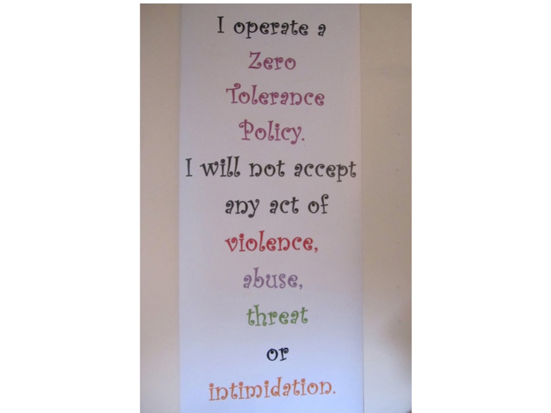 Printed words on narrow white paper read down the page: I operate a zero tolerance policy. I will not accept any act of violence, abuse, threat or intimidation.